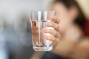 A shallow depth of field photo of a hand holding out a glass of water.