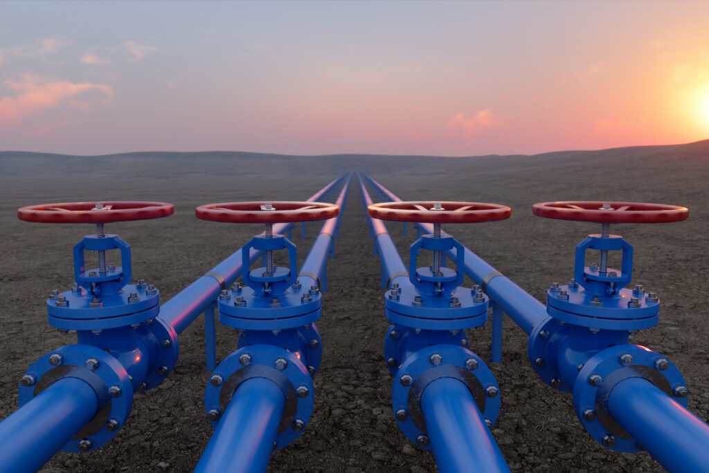 A row of four blue pipes with red handles, stretching into the distance of a grassy landscape.