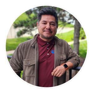 Photo of Enrique Chávez Jr., outside and wearing a brown jacket and red polo