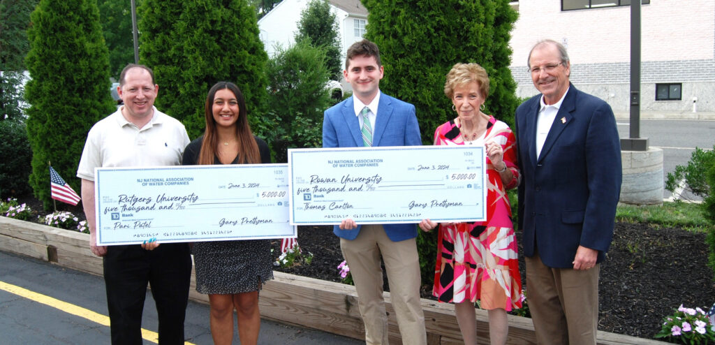 Group of five people, with two the students holding their checks for receiving the scholarships